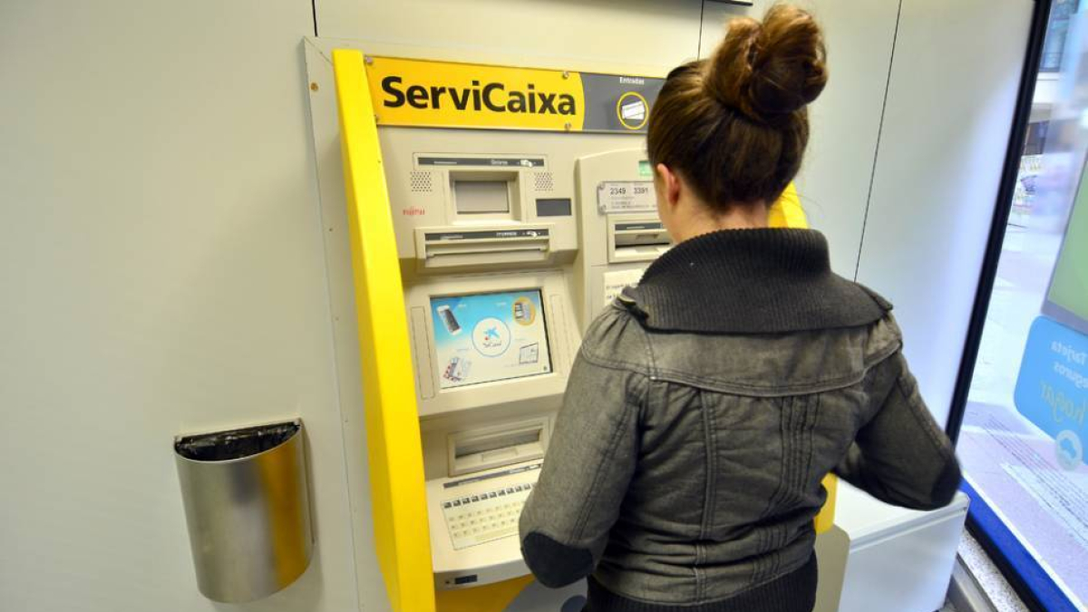 Una mujer sacando dinero en una entidad financiera en una imagen de archivo.-HDS