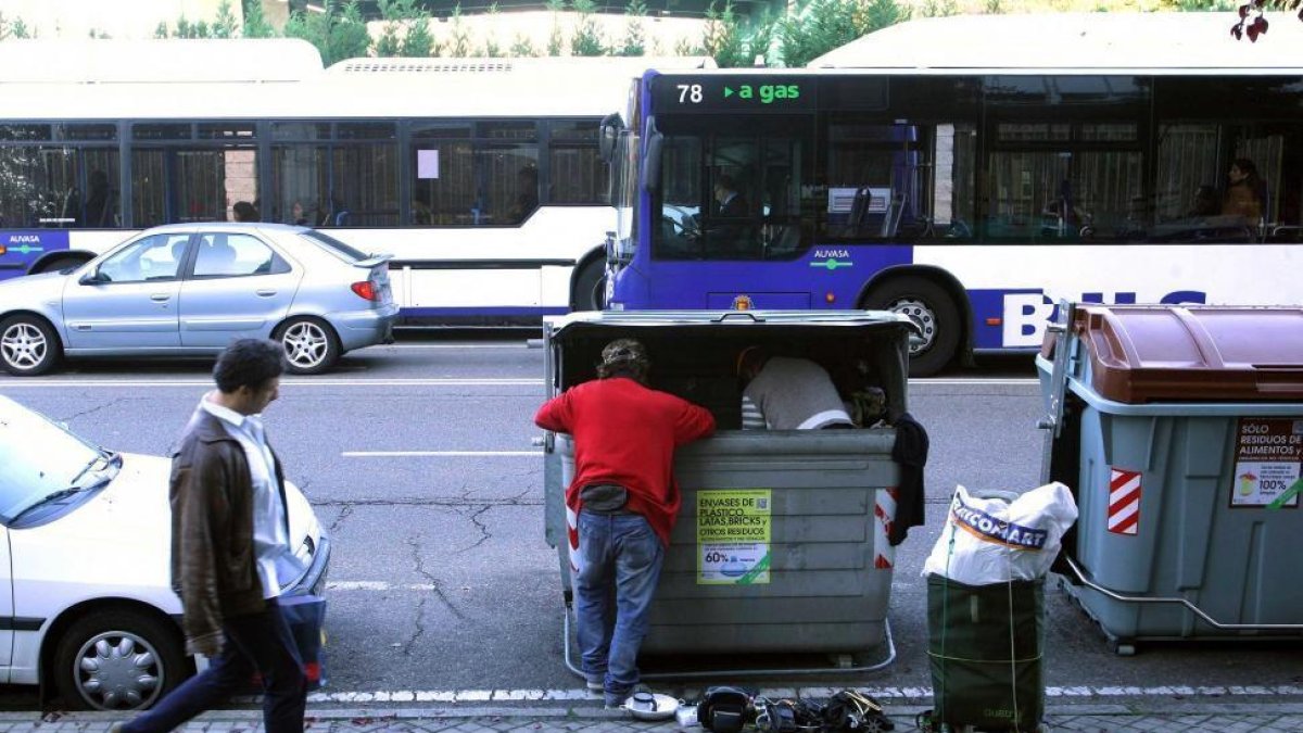 Dos personas recopilan enseres de un contenedor de basura-ICAL