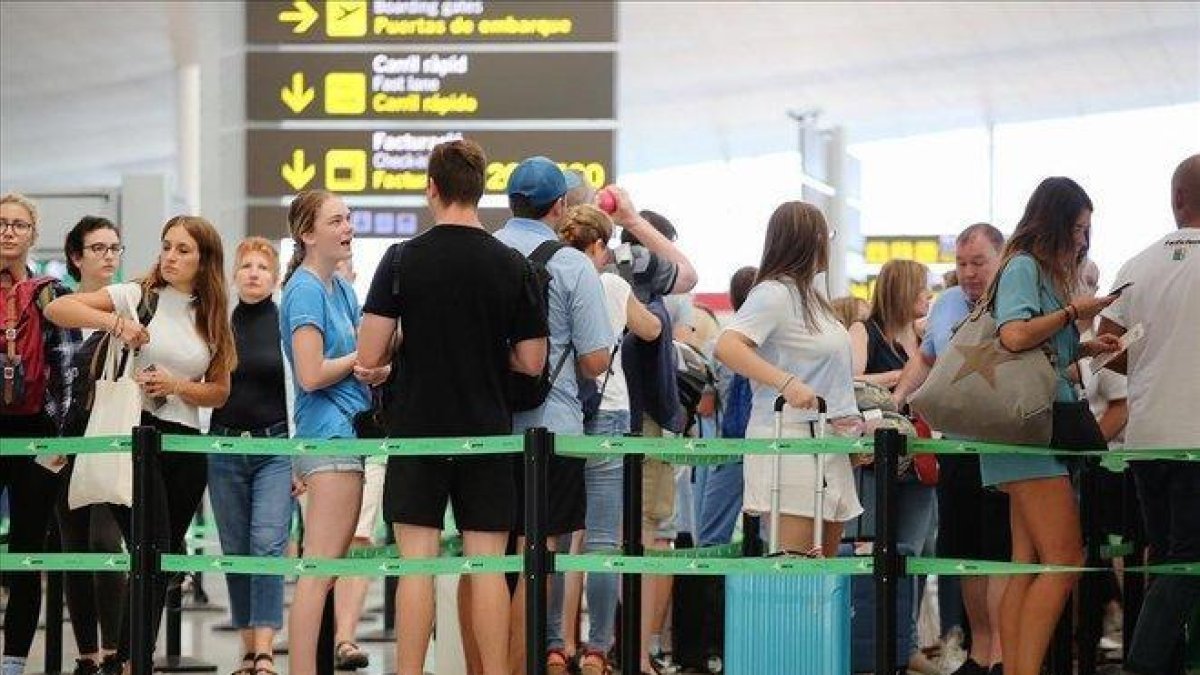Pasajeros esperan para pasar los controles de seguridad en el aeropuerto de El Prat.-JOAN CORTADELLAS