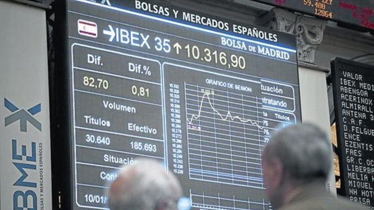 Dos inversores observan una pantalla con la evolución del Ibex 35 en la Bolsa de Madrid.-ARCHIVO / EFE
