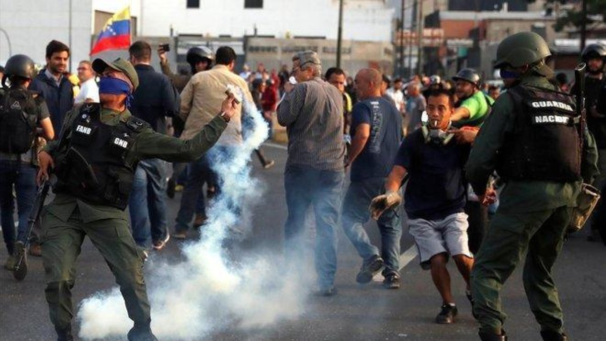 Un militar lanza un bote de gas lacrimógeno durante los disturbios en Caracas-CARLOS GARCIA RAWLINS (REUTERS)