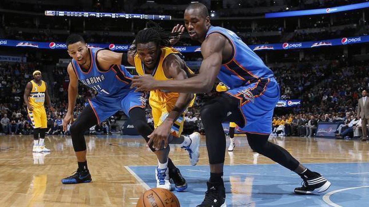 Andre Roberson y Serge Ibaka corren por el balón, en el choque entre los Thunder y los Nuggets en Denver.-Foto:   AP / DAVID ZALUBOWSKI
