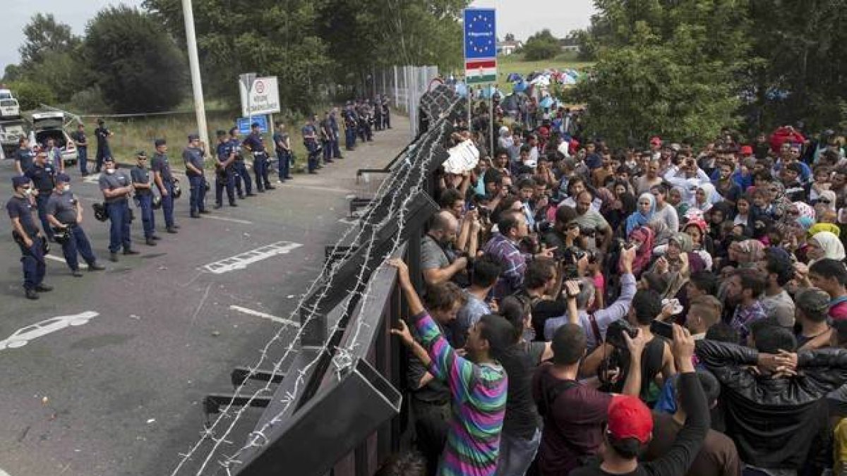 Refugiados sirios ante la valla fronteriza de Hungría.-MARKO DJURICA / REUTERS