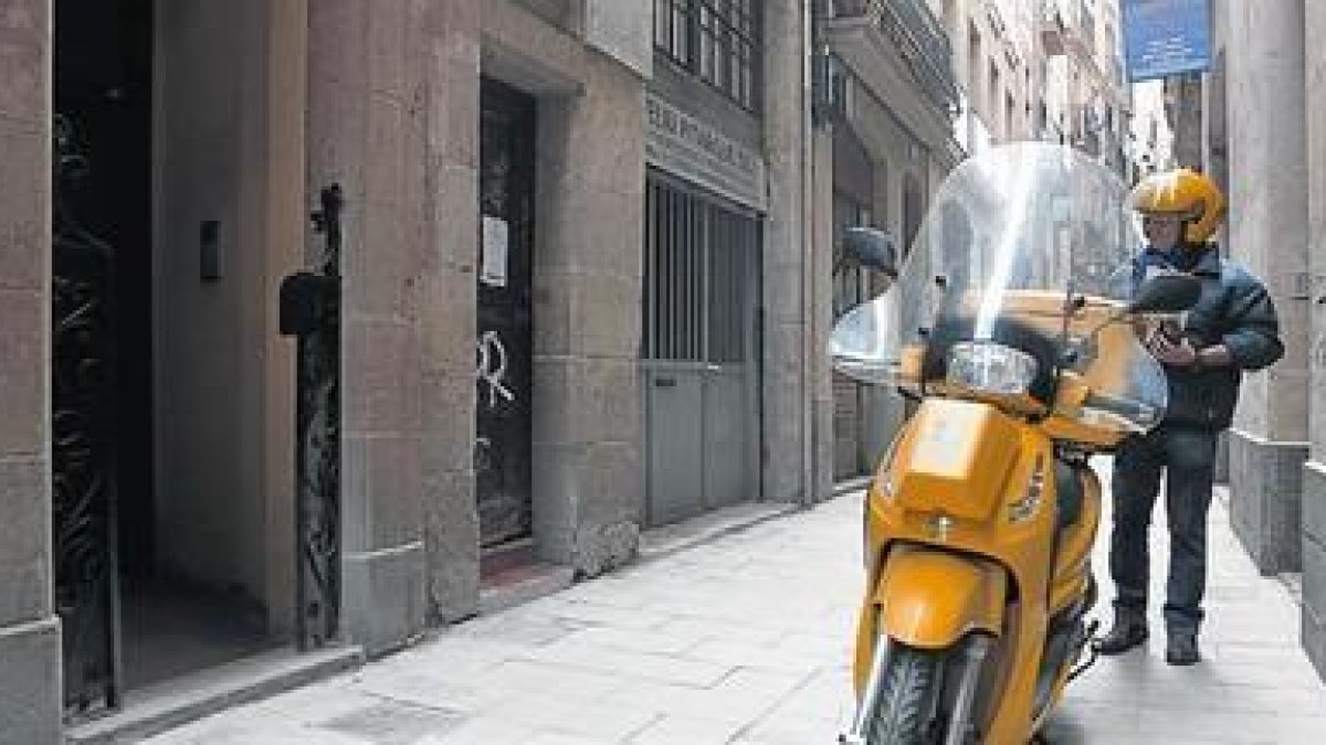 Un cartero en Barcelona, a punto de entregar un carta.-FERRAN NADEU