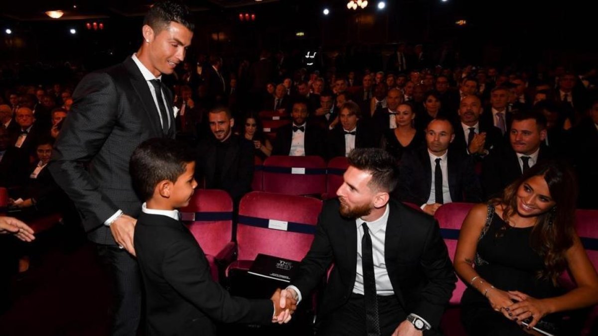 El hijo de Cristiano saluda a Messi en presencia de su padre y Antonella, en Londres.-AFP / BEN STANSALL