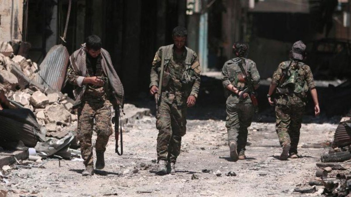 Combatientes de las Fuerzas Democráticas de Siria caminan sobre los escombros de tiendas y edificios dañados por la batalla en la ciudad de Manbij.-RODI SAID (REUTERS)