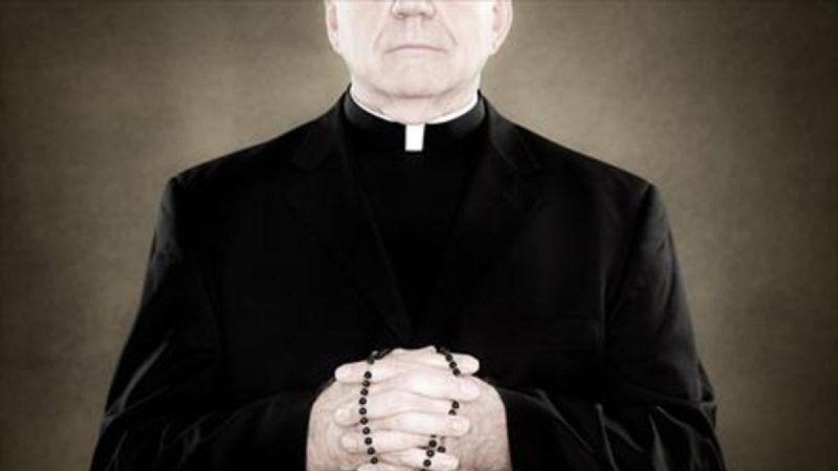 Un sacerdote sujeta un rosario.-EL PERIÓDICO