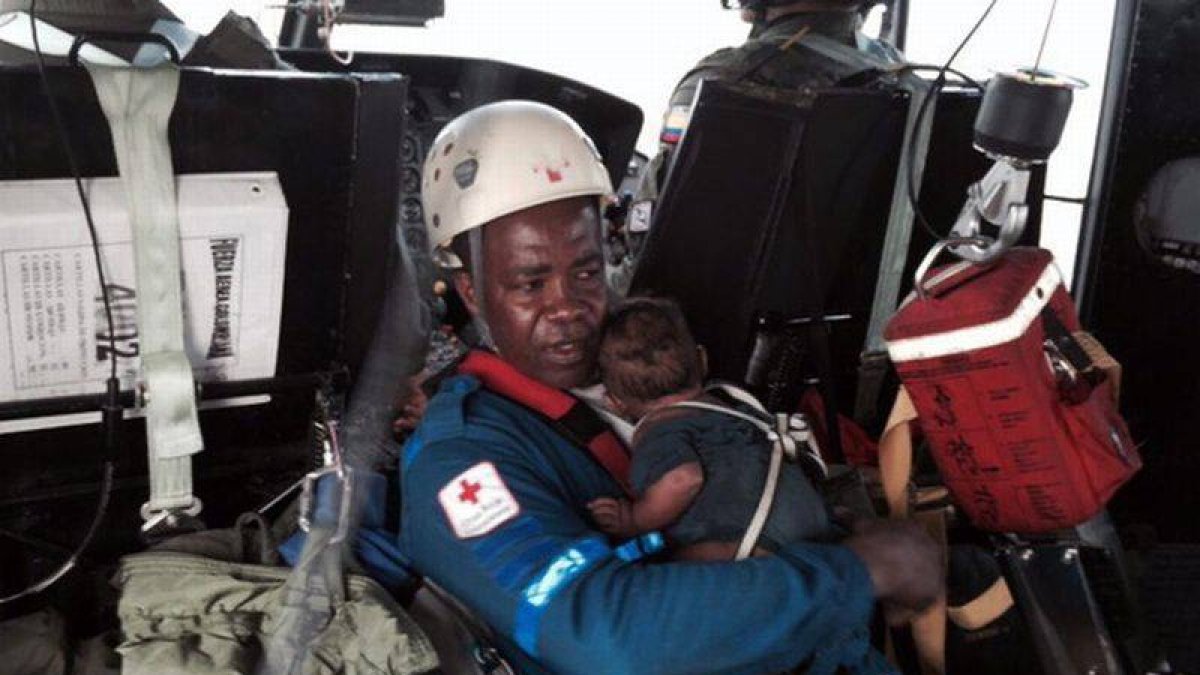 Un integrante de la Cruz Roja lleva al bebé rescatado tras pasar cinco días perdido con su madre en la selva colombiana.-Foto: EFE