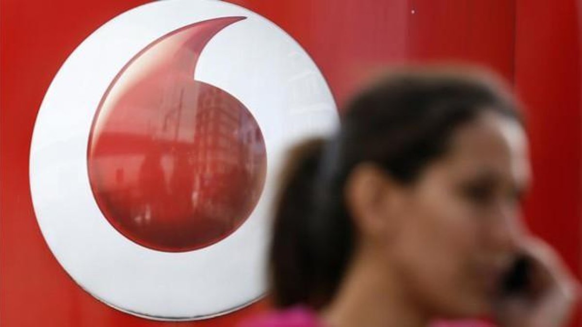 Una mujer habla por móvil frente a un anuncio de Vodafone.-REUTERS