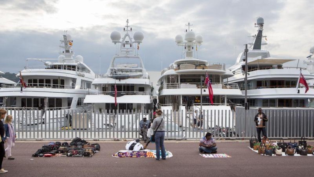 Barcos de lujo y manteros en el Port Vell de Barcelona.-ARCHIVO / FERRAN NADEU