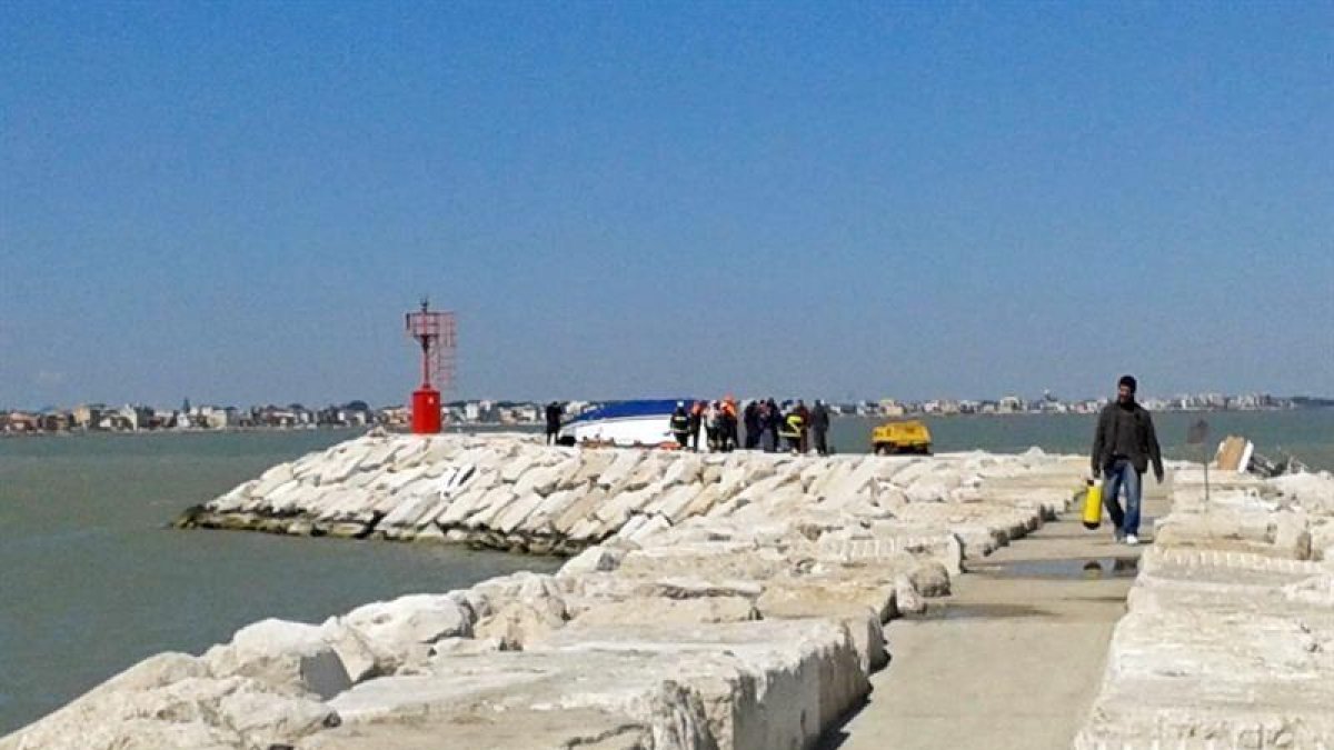 Bomberos y miembros de los servicios de rescate trabajan junto al casco de un barco tras su naufragio en Rimini.-EFE