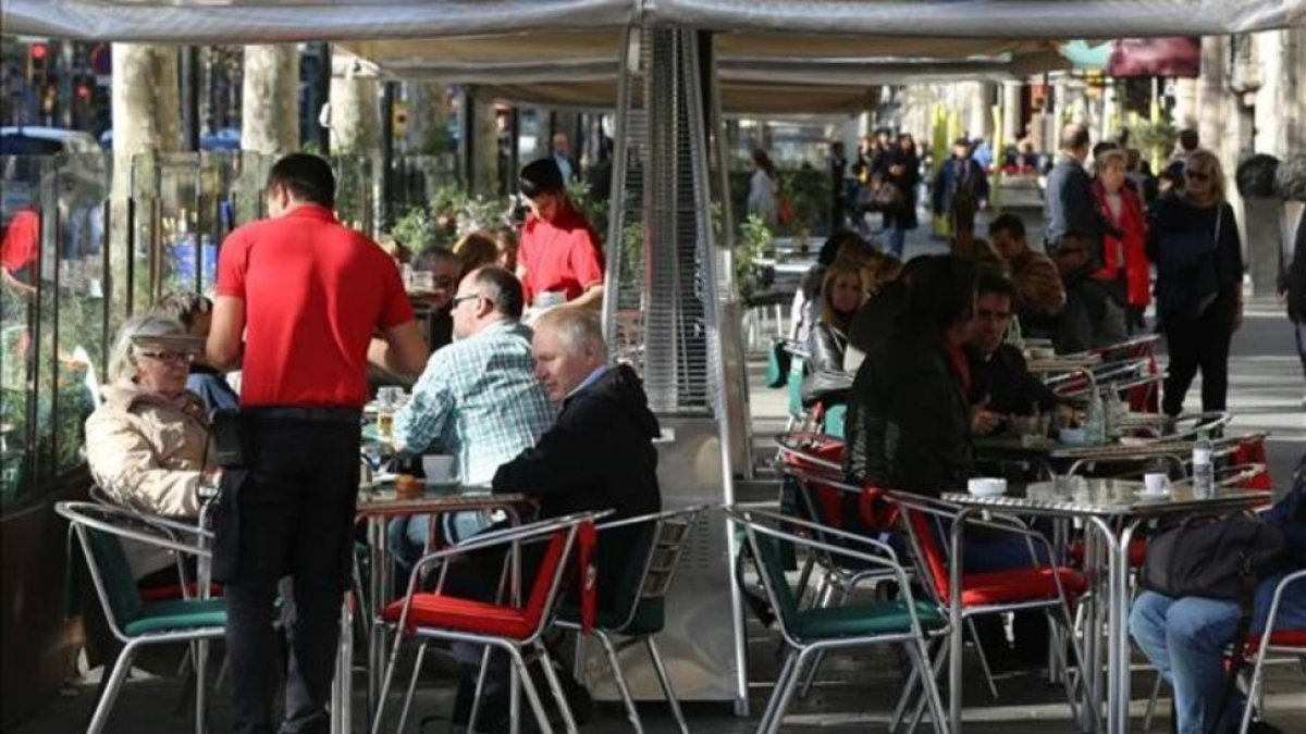 Un camarero atiende a clientes en una terraza. Es el colectivo con más contratos temporales.-DANNY CAMINAL
