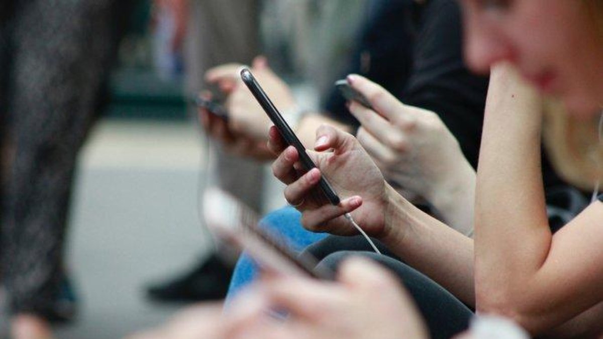 Un grupo de personas consulta sus teléfonos móviles.