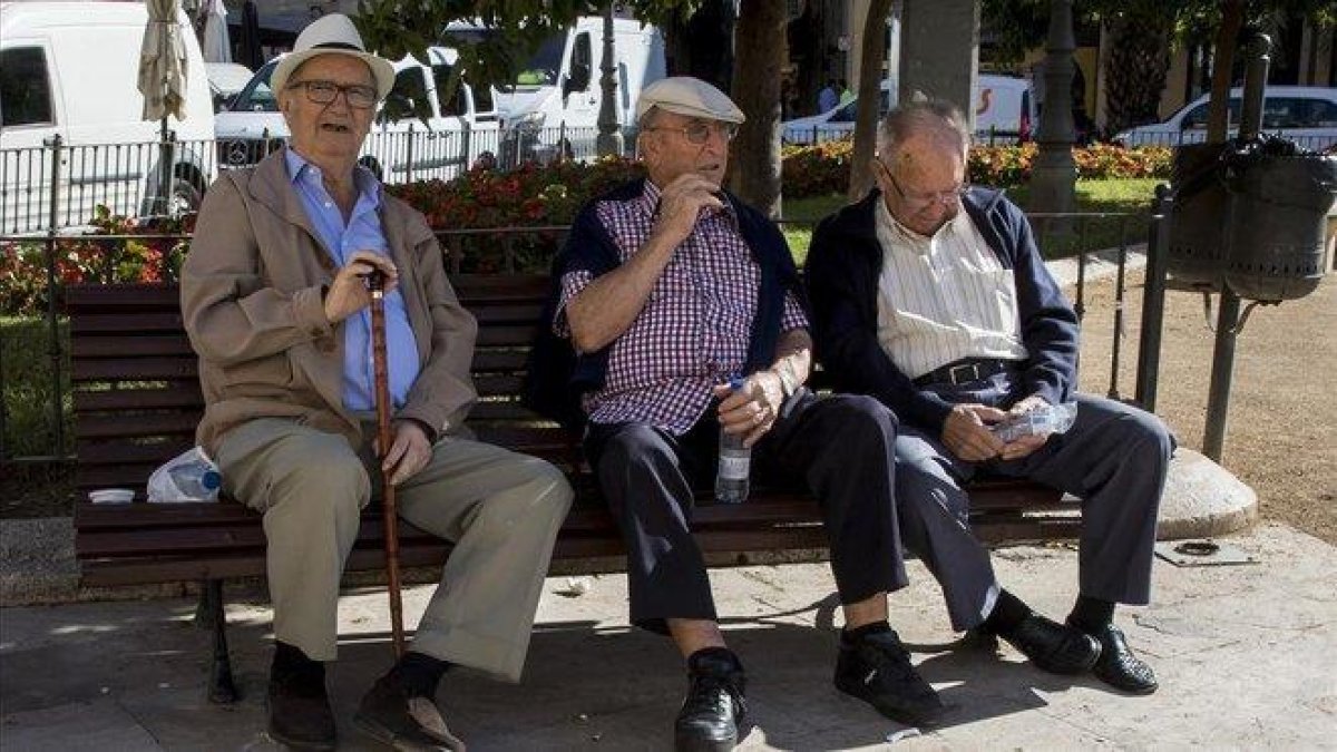 Tres jubilados descansan en un banco de un parque en Valencia.-MIGUEL LORENZO