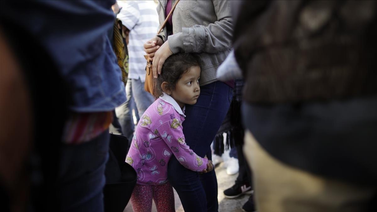 Una niña mexicana con su madre espera con otros inmigrantes en la frontera la respuesta a la solicitud de asilo político en EEUU. /-GREGORY BULL (AP)