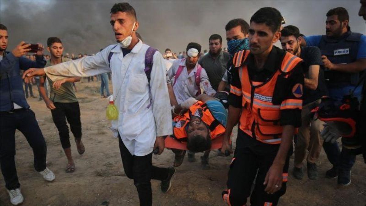 Personal sanitario palestino trasladan a un manifestante herido durante los enfrentamientos con las fuerzas israelís al este de la ciudad de Gaza.-SAID KHATIB (AFP)