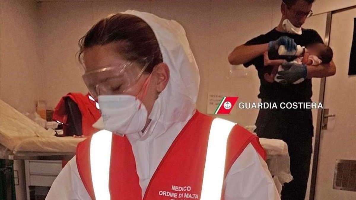 Miembros de la Guardia Costera italiana alimentan a bebés recién nacidos que han sido rescatados ante las costas de Libia.-