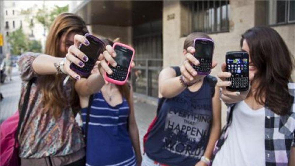 Unas adolescentes muestran sus teléfonos móviles a la puerta de su instituto en Barcelona.-