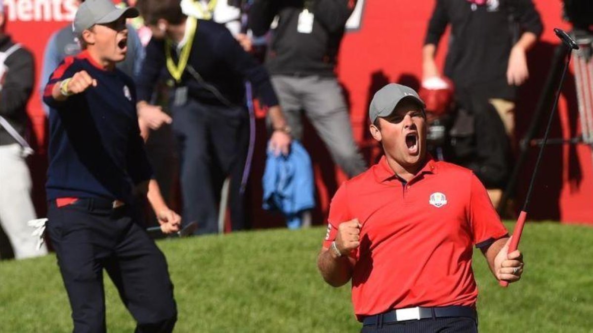 Patrick Reed celebra exultante, con Jordan Spieth al fondo, la victoria sobre los europeos Rose y Stenson en la sesión matinal de la primera jornada de la Ryder.-AFP / TIMOTHY A. CLARY