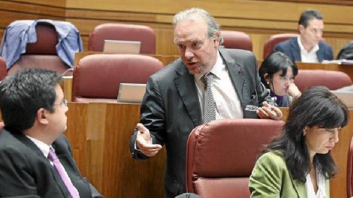 El procurador socialista José Francisco Martín (de pie) conversa con Óscar López durante el pleno. / ICAL-