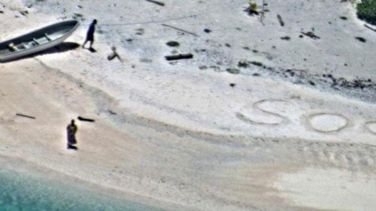 SOS escrito en la arena de playa por  Linus y Sabina Jack.-US NAVY