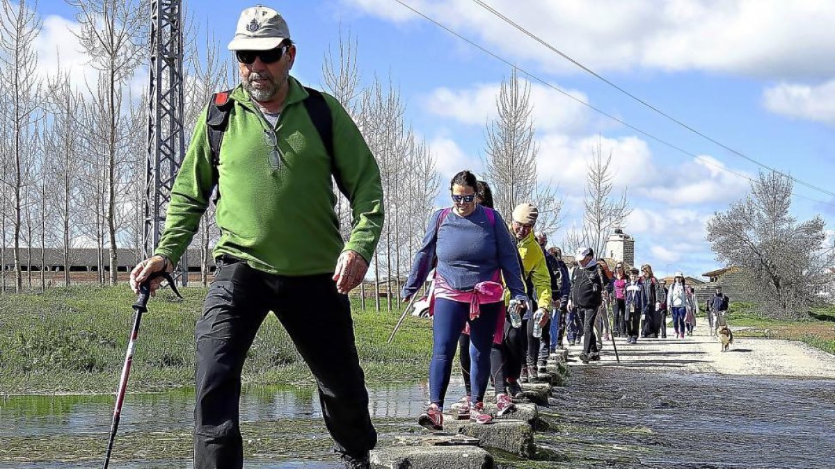 Un grupo de caminantes cruza uno de los arroyos de a ruta-L,P.