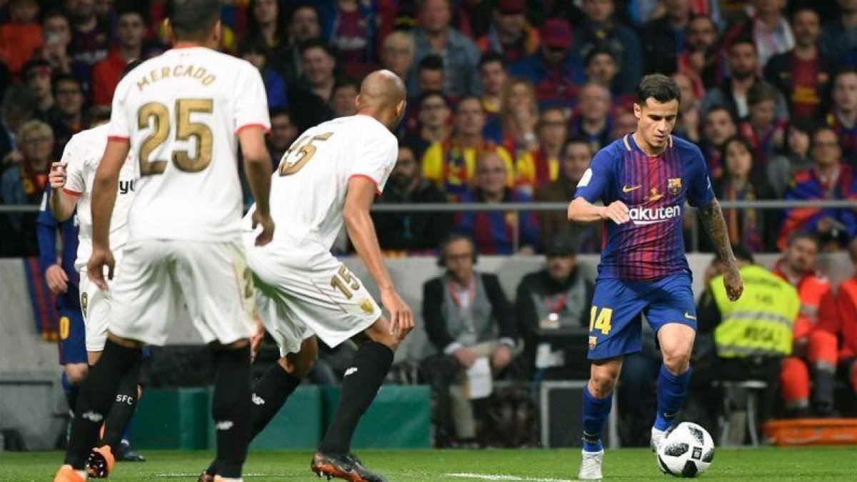 Coutinho conduce el balón ante Nzonzi y Mercado en el Metropolitano.-AFP / PIERRE-PHILIPPE MARCOU