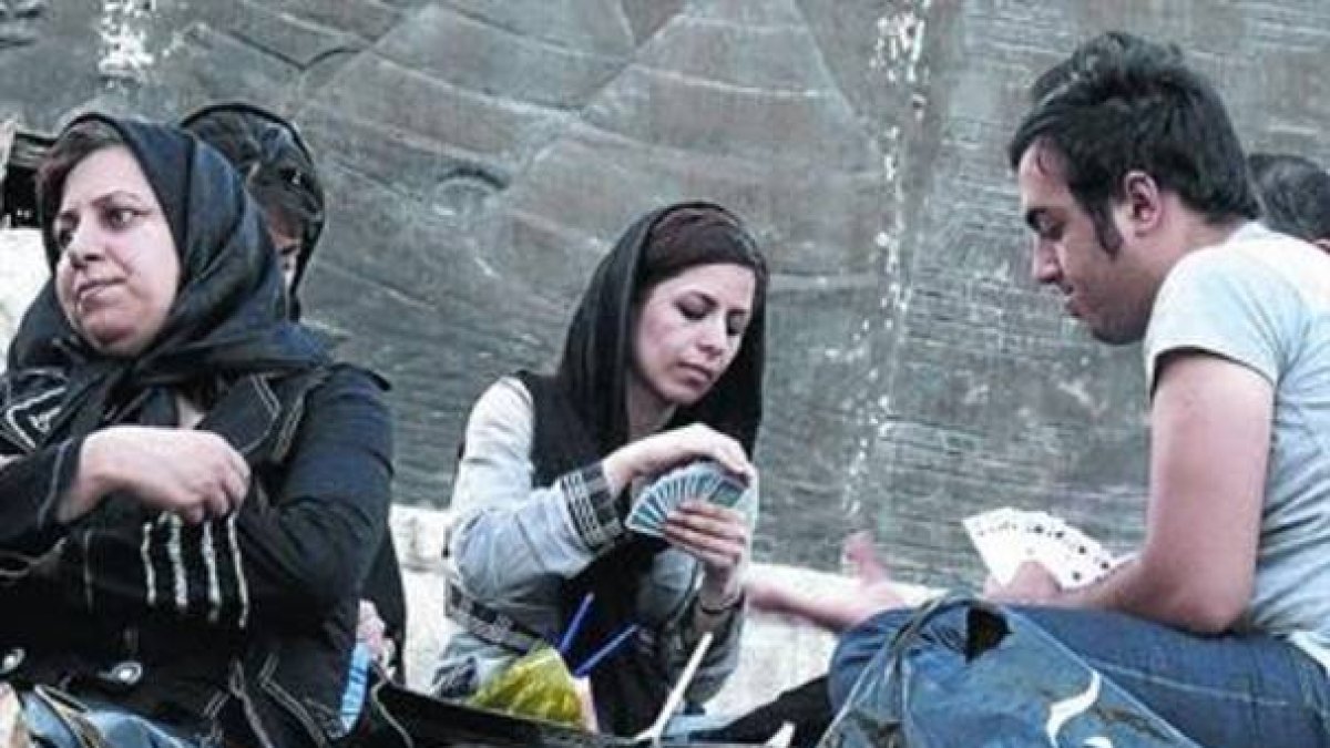 De picnic. Unos jóvenes iranís juegan a las cartas ¿pese a que está prohibido¿ en un parque de Teherán.-Foto:   AFP /ATTA KENARE