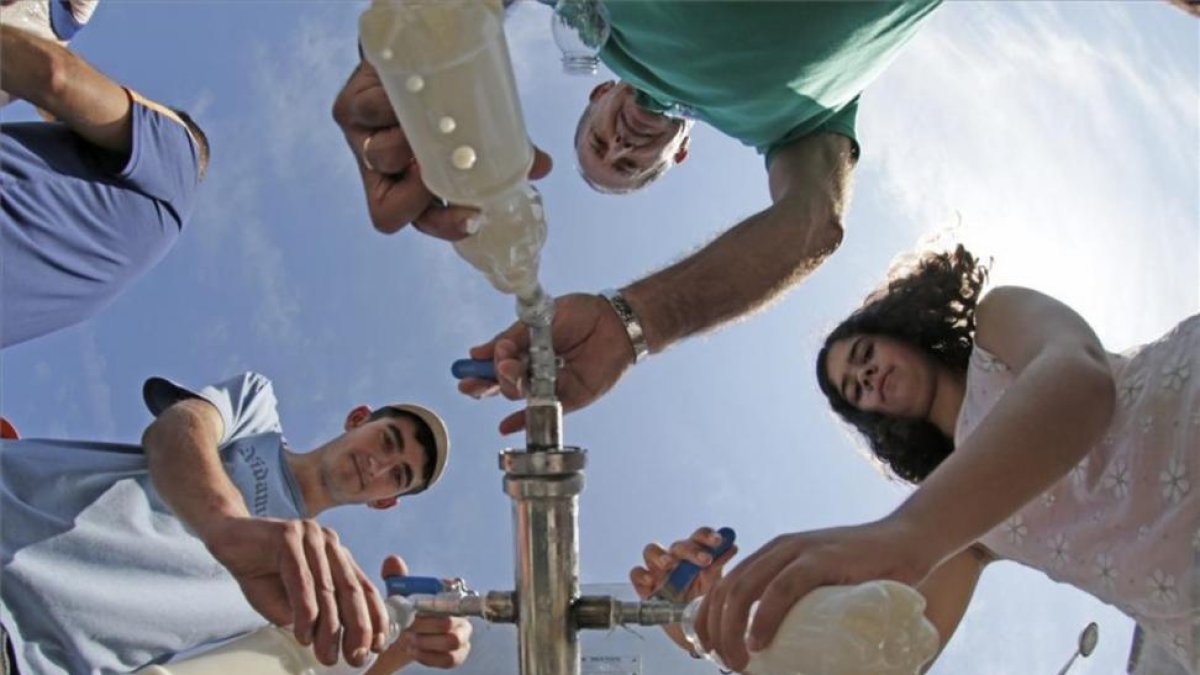 Vecinos recogen leche regalada por ganaderos de una cisterna en frente a un centro comercial en el 2015 en Pontevedra.-EFE / LAVANDEIRA