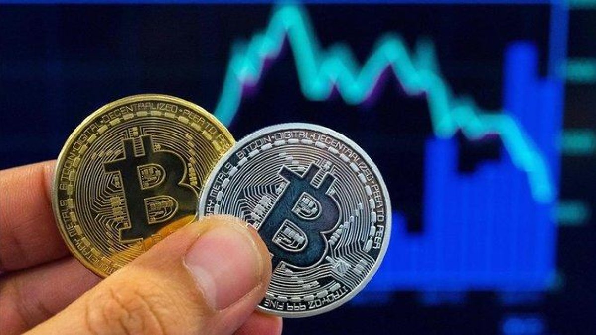 Una persona con dos representaciones físicas del Bitcoin.-AFP