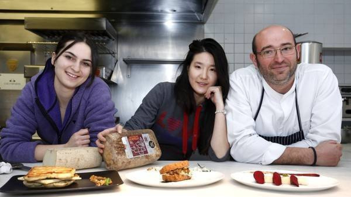 Las alumnas del Basque Culinary Center de San Sebastián, María y Yao Yao, preparan en el restaurante Cocinandos de León, bocadillos con queso artesanal Los Payuelos. Junto a ellas, el chef y propietario del restaurante, Juanjo Pérez-Carlos S. Campillo / ICAL