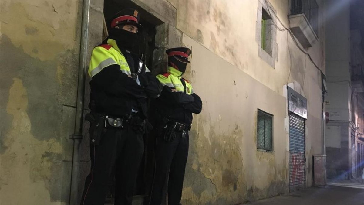 Dos mossos ante el portal de la calle de la Riera Alta donde se ha cometido el crimen.-/ GUILLEM SÀNCHEZ