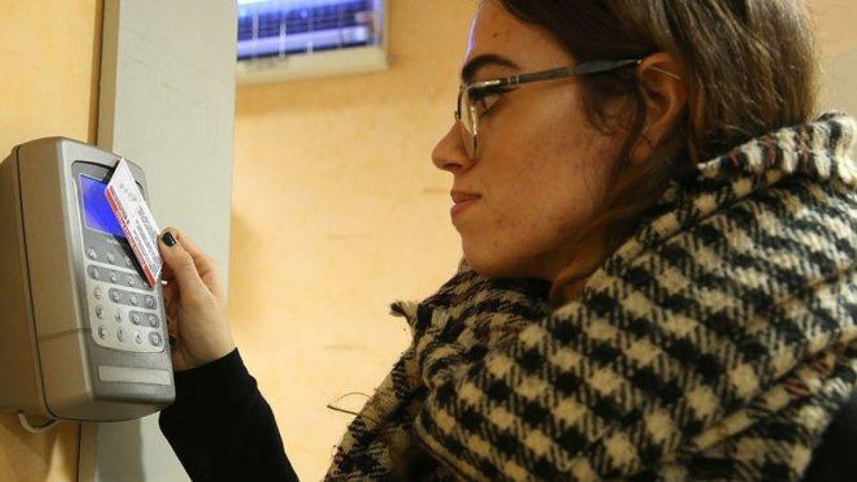 Una trabajadora ficha en un aparato de control horario al empezar su jornada laboral.-ELISENDA PONS
