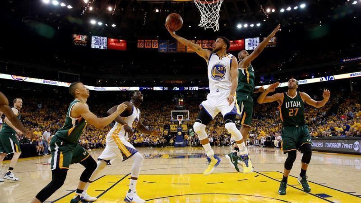 El jugador de los Warriors de Golden State Stephen Curry (c) entra a canasta a pesar de la defensa de Boris Diaw (2º dcha) y Rudy Gobert (dcha).-EFE
