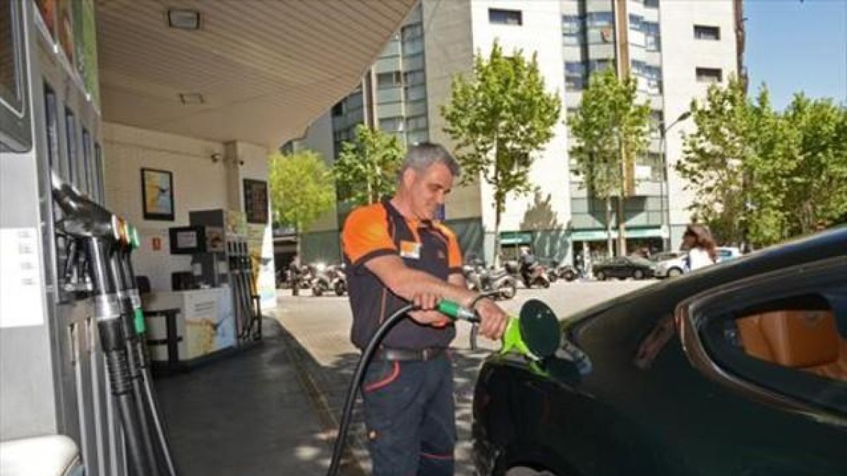 Un empleado llena un depósito en una gasolinera de Barcelona.-MÓNICA TUDELA