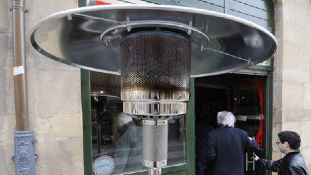 Dos personas entran a un bar de la capital soriana que dispone de una seta calefactora en su exterior. / VALENTÍN GUISANDE-