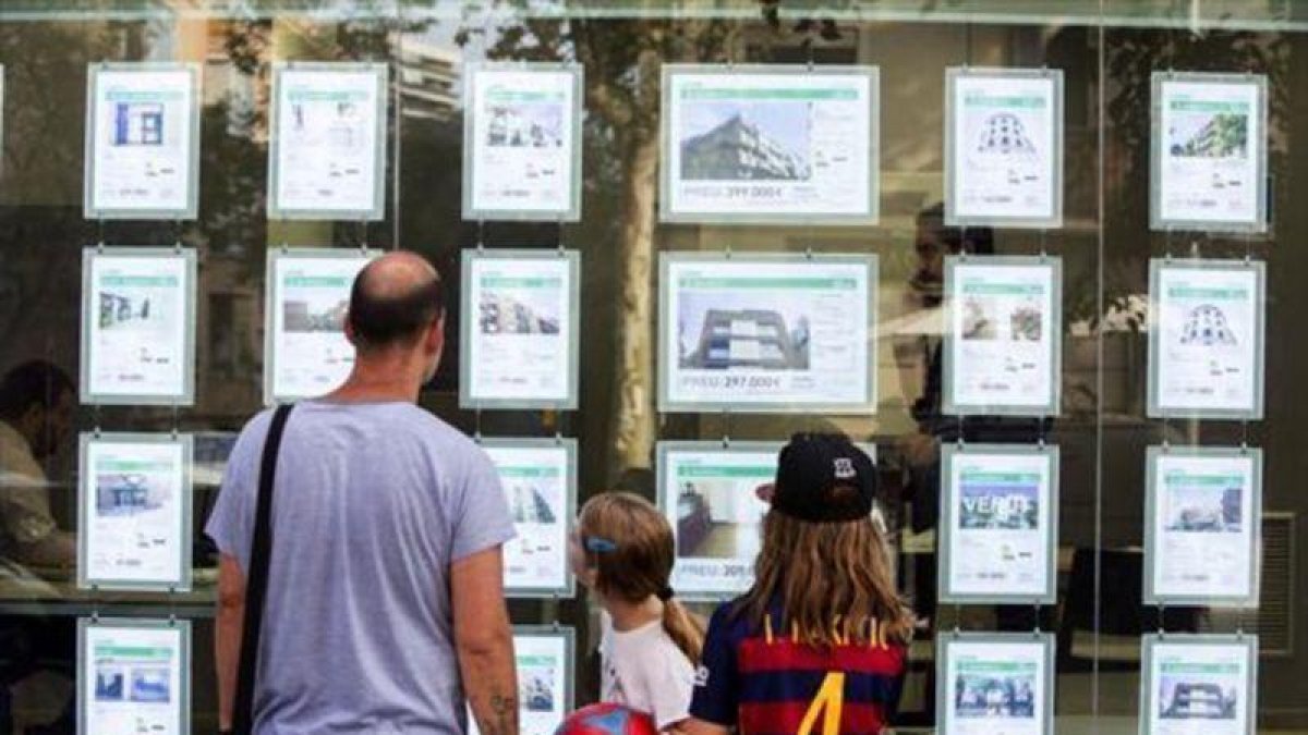 Una familia delante de una oficina inmobiliaria.-FERRAN NADEU