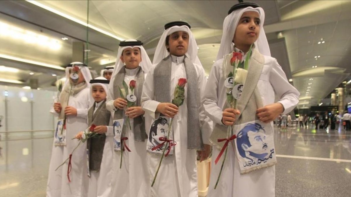 Niños qatarís con flores e imágenes del emir Al Thani reciben a ciudadanos de Kuwait y Omán, países que no se han sumado al boicot, en el aeropuerto de Doha.-REUTERS / NASEEM ZEITOON
