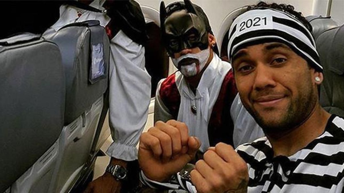 Alves, vestido de presidiario, junto a Suárez, con un disfraz de Batman, en el avión de regreso a Barcelona.-TWITTER