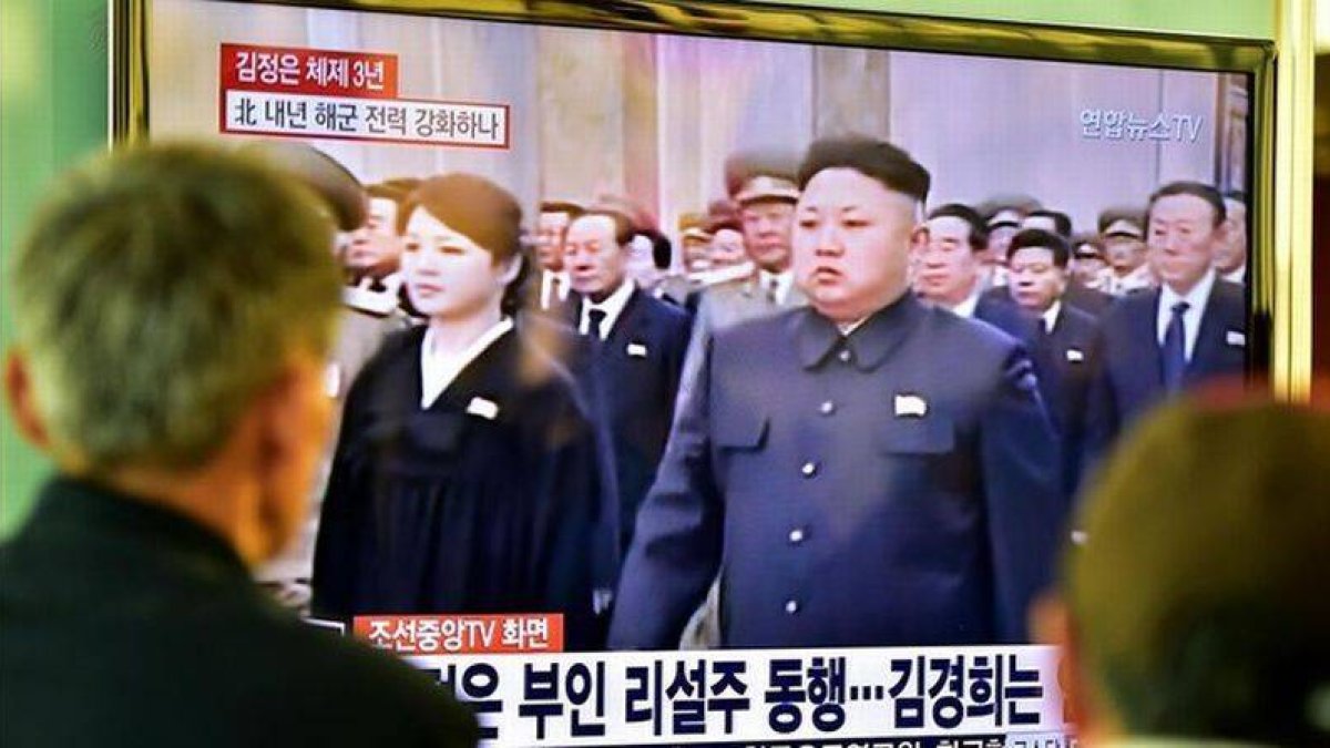 Dos personas miran en una gran pantalla de televisión la retransmisión de la ceremonia de conmemoración, en una estación de trenes de Seúl (Corea del Sur).-Foto: AFP / JUNG YEONG-JE