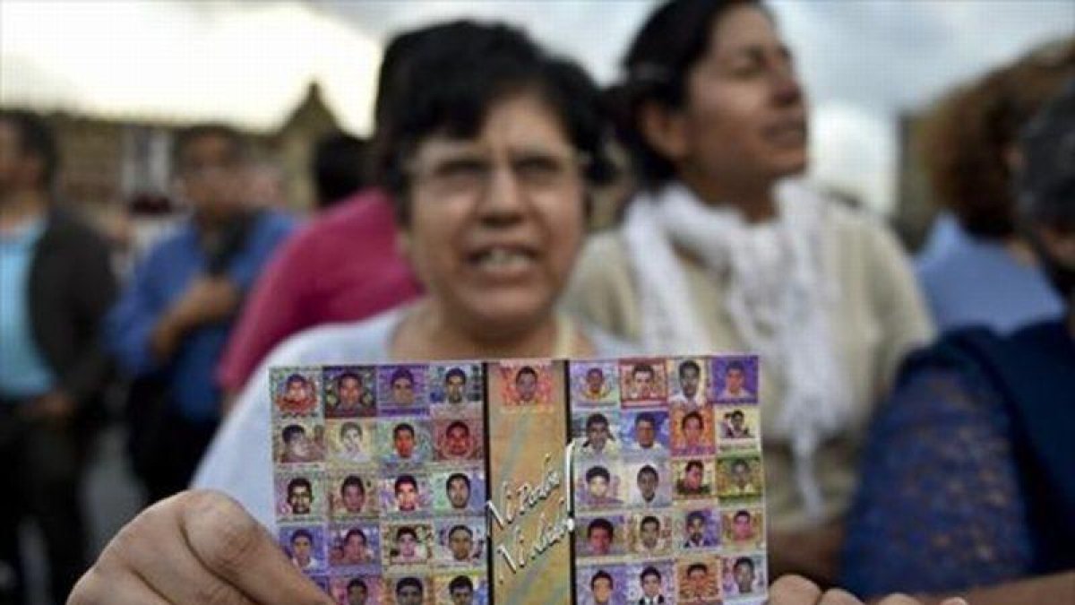 Una mujer muestra la foto de los estudiantes de Ayotzinapa.-AFP / YURI CORTEZ