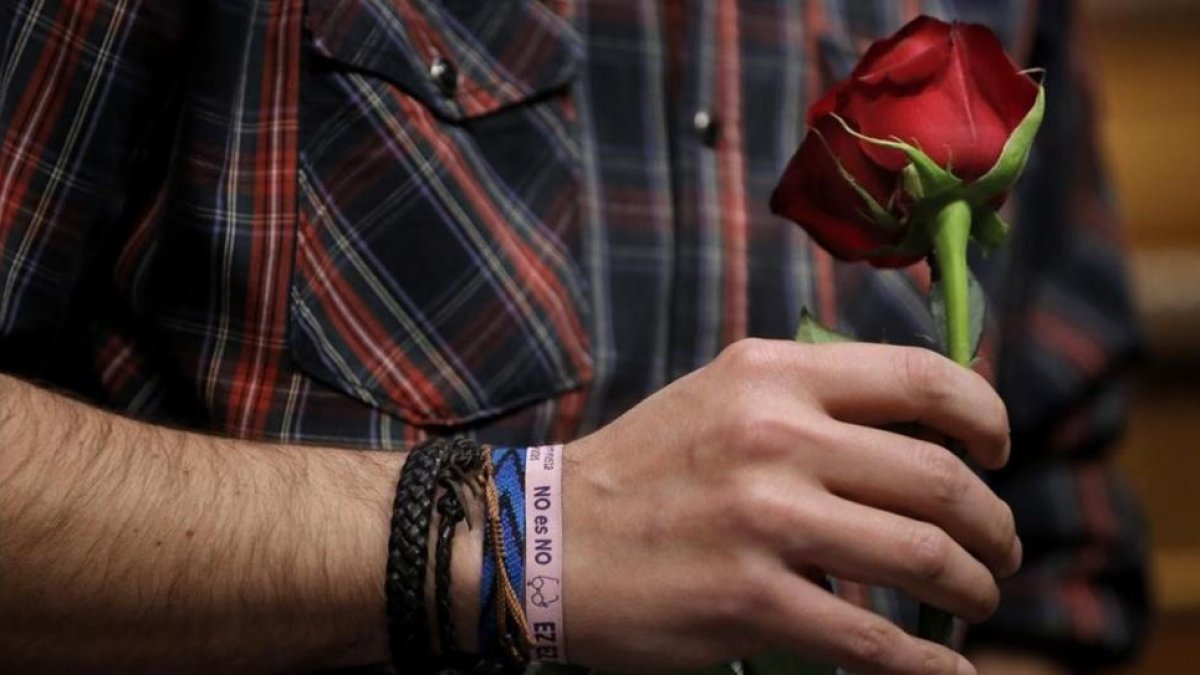Iglesias sostiene una rosa con la mano en la que luce una pulsera podemista con el lema de Sánchez contra la abstención del PSOE en la investidura de Rajoy.-JOSE LUIS ROCA