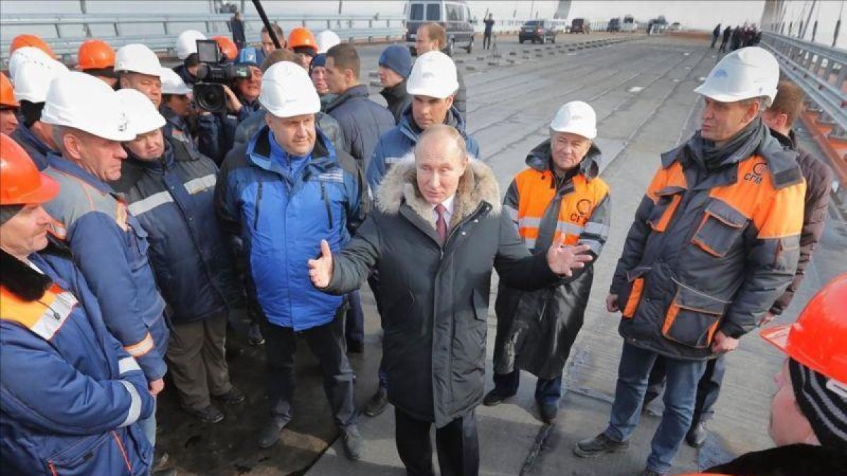 El presidente ruso, Vladimir Putin (centro) conversa con varios obreros durante la visita a las obras de construcción del puente de Crimea sobre el estrecho de Kerch, el pasado marzo.-YURI KOCHETKOV (EFE)
