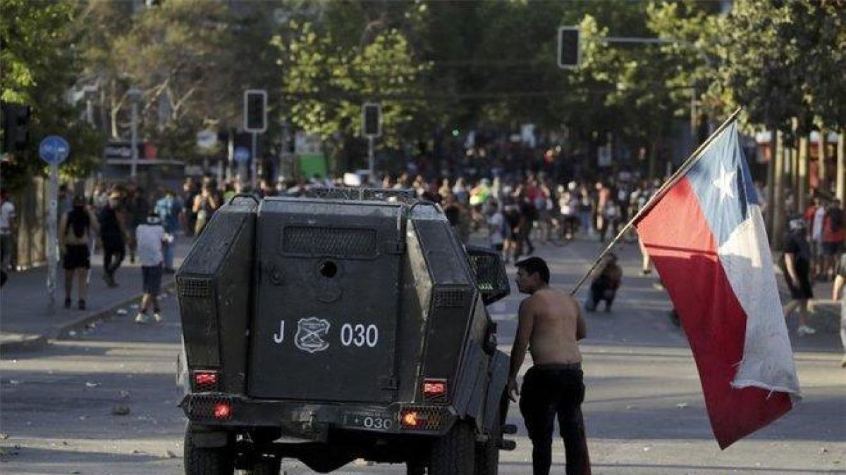 Un manifestante se enfrenta a un vehículo militar durante las protestas en Chile.-AP