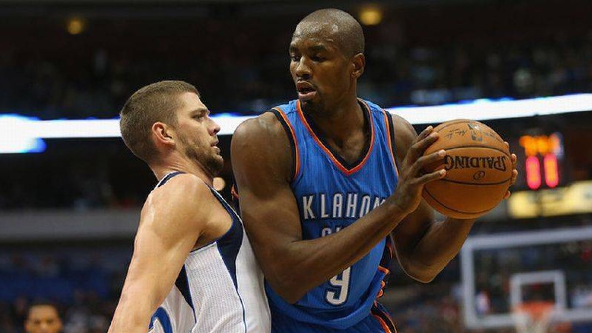 Serge Ibaka trata de deshacerse de Chandler Parsons, en el partido entre los Thunder y los Mavericks.-Foto: AFP / RONALD MARTINEZ