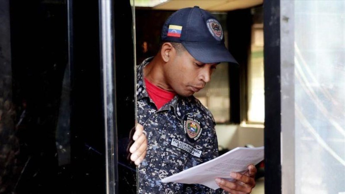 Un polícía de Caracas lee la ley de amnistía distribuida por la oposición.-EL PERIÓDICO