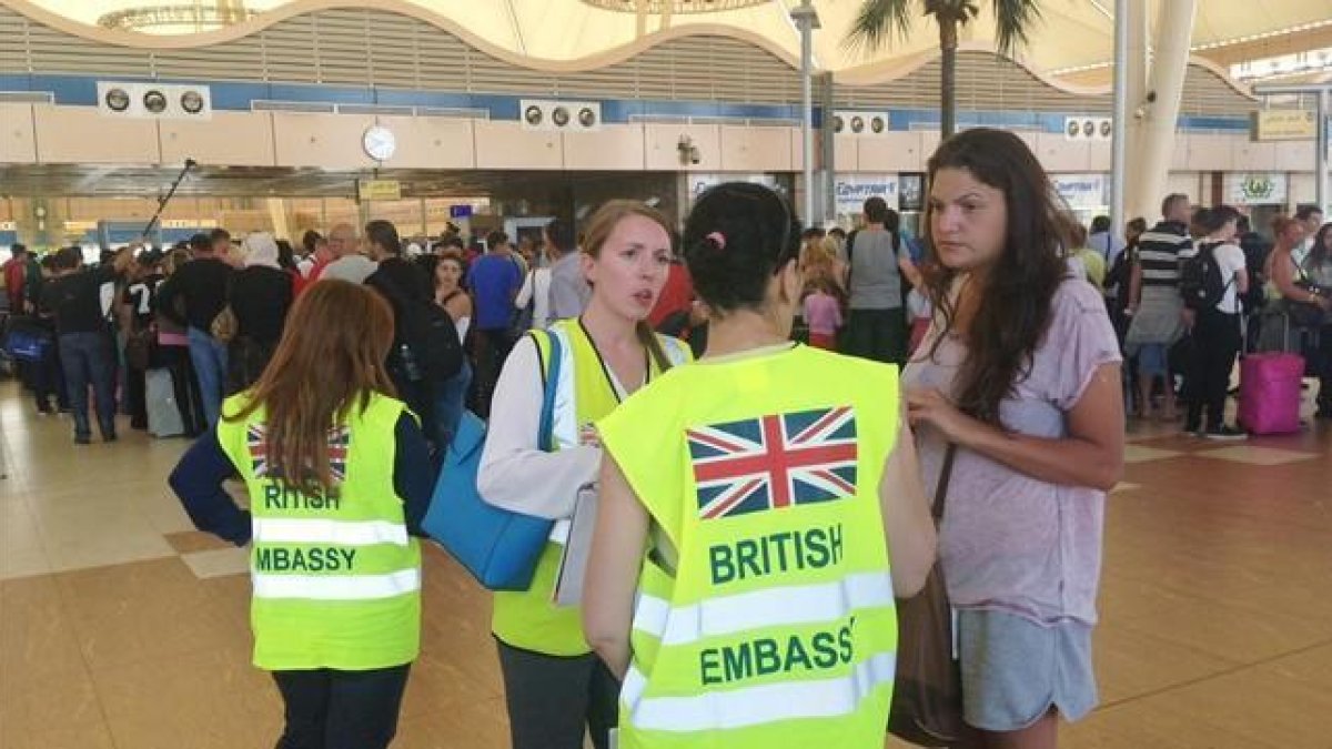 Una turista habla con personal de la Embajada británica en Egipto mientras otros hacen cola para el 'check in', en el aeropuerto de Sharm al Sheij, este viernes.-AP / THOMAS HARTWELL