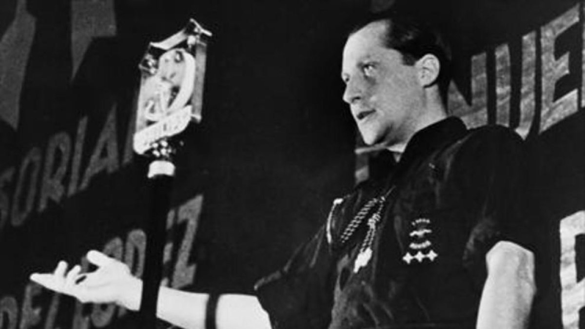 José Antonio Primo de Rivera, llevando la clásica camisa azul de Falange Española, con el yugo y las flechas bordados en el pecho, en un mítin del partido.-