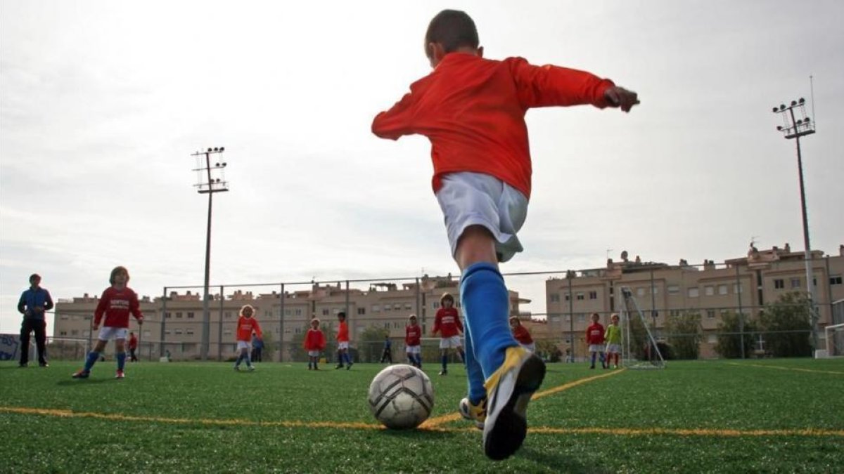 Un niño se apresta a chutar durante un partido de fútbol base.-