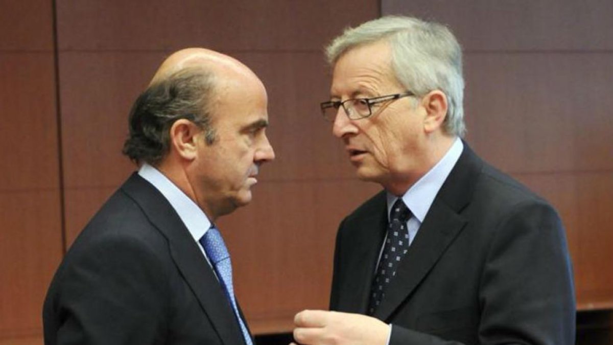 El ministro de Economía, Luis de Guindos, conversa con el presidente Jean-Claude Juncker.-AFP / THIERRY CHARLIER